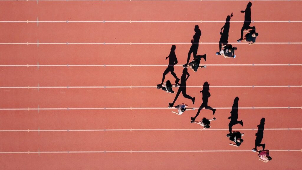 Groep mensen loopt ontspannen over een atletiekbaan, met focus op ritme en herstelgericht sporten